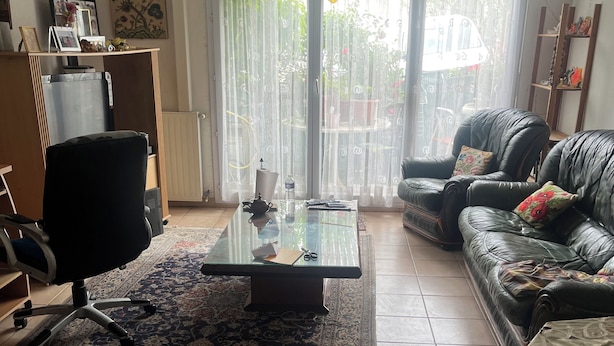 A living room with a glass coffee table, leather sofa, and a patterned rug. - Comfortable apartment (Montpellier)