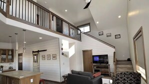 Un vaste espace de vie comprenant une cuisine, un coin repas et un escalier menant à une mezzanine.