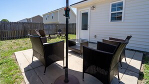 An outdoor patio with wicker furniture and a table under a canopy. - Quaint Cottage-3BR/2B House with Arcade and Fire Pit in Quiet Part of Hope Mills (Hope Mills)