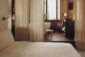 A hotel room with a bed, a bathroom with a sink and mirror, and curtains. - Mona Athens (Athens)
