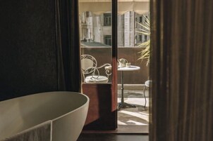 A bathroom with a large bathtub, a small round table with a chair, and a mirror.