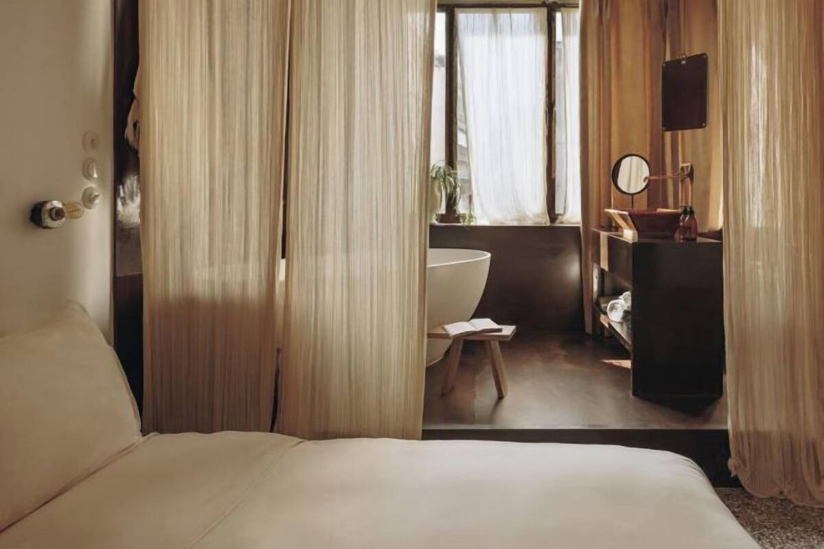 Un dormitorio con cama, un baño con bañera y un tocador con espejo.