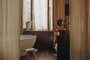 A bathroom with a bathtub, a mirror, and a window with curtains. - Mona Athens (Athens)