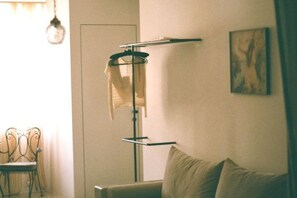 A room with a hanging clothes rack, a chair, and a sofa. - Mona Athens (Athens)