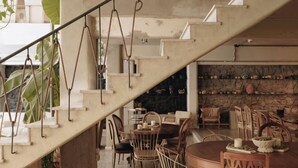 A staircase leading to a dining area with chairs and tables, a stone wall, and hanging plants. - Mona Athens (Athens)