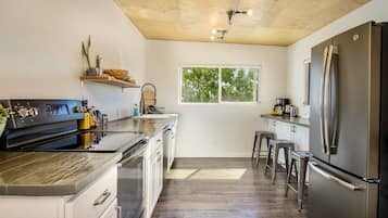 A modern kitchen with a central island, stainless steel appliances, and a window providing natural light.