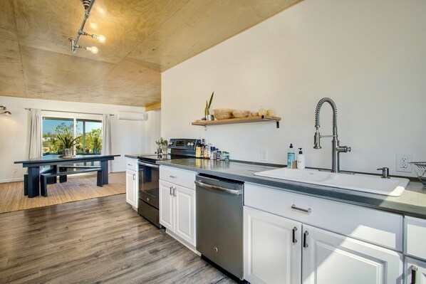 Una cocina moderna con armarios blancos, lavavajillas de acero inoxidable y encimera de madera.