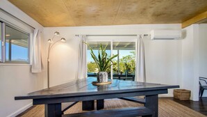 Un comedor moderno con una mesa de madera oscura, una planta en maceta y vistas al exterior a través de amplios ventanales.