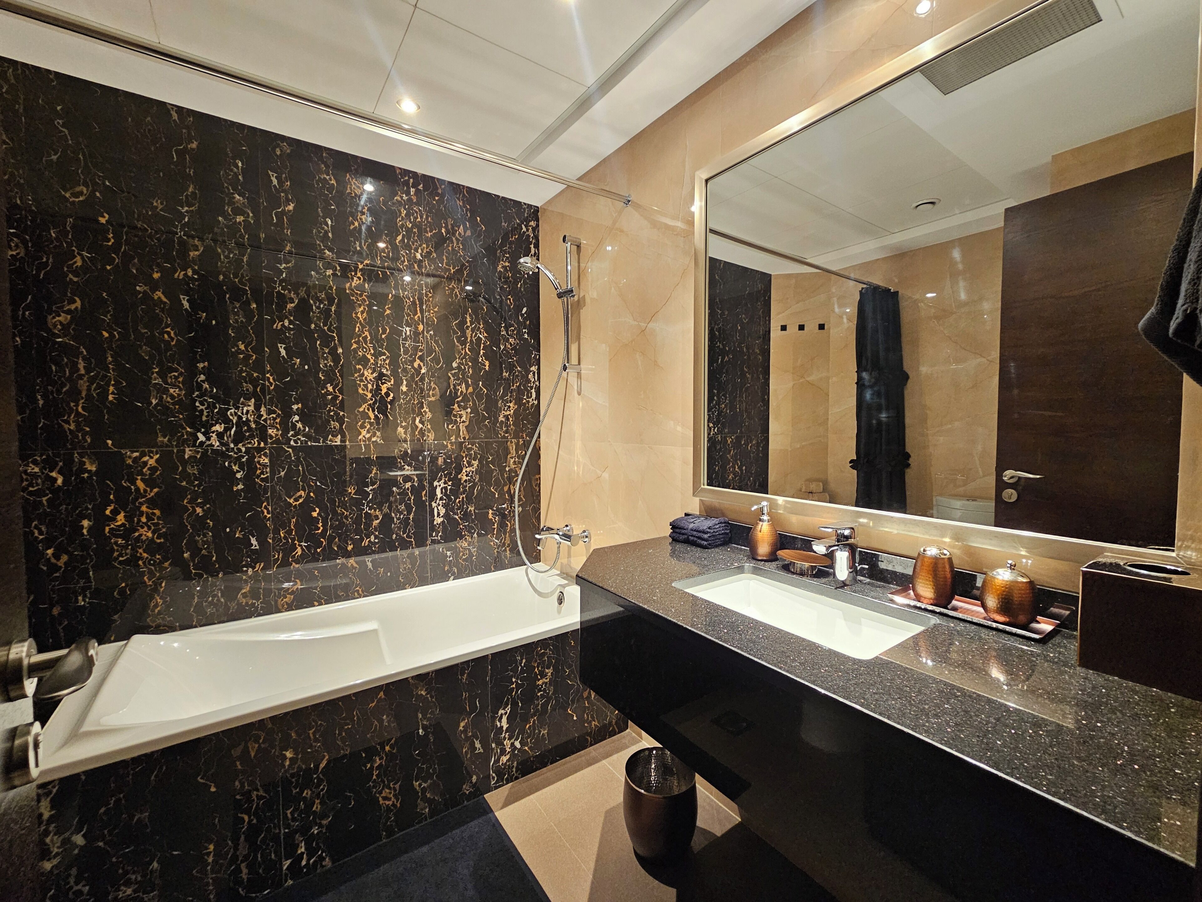 Een moderne badkamer met een grote spiegel, een badkuip en een wastafelmeubel met een wastafel.