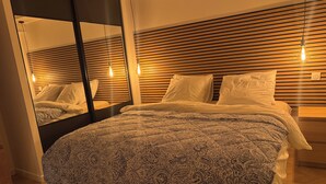 A modern bedroom with a patterned bedspread, wooden headboard, and bedside lamps.