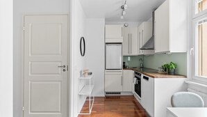 Een kleine keuken met witte kastjes, een ingebouwde oven en een houten aanrecht.