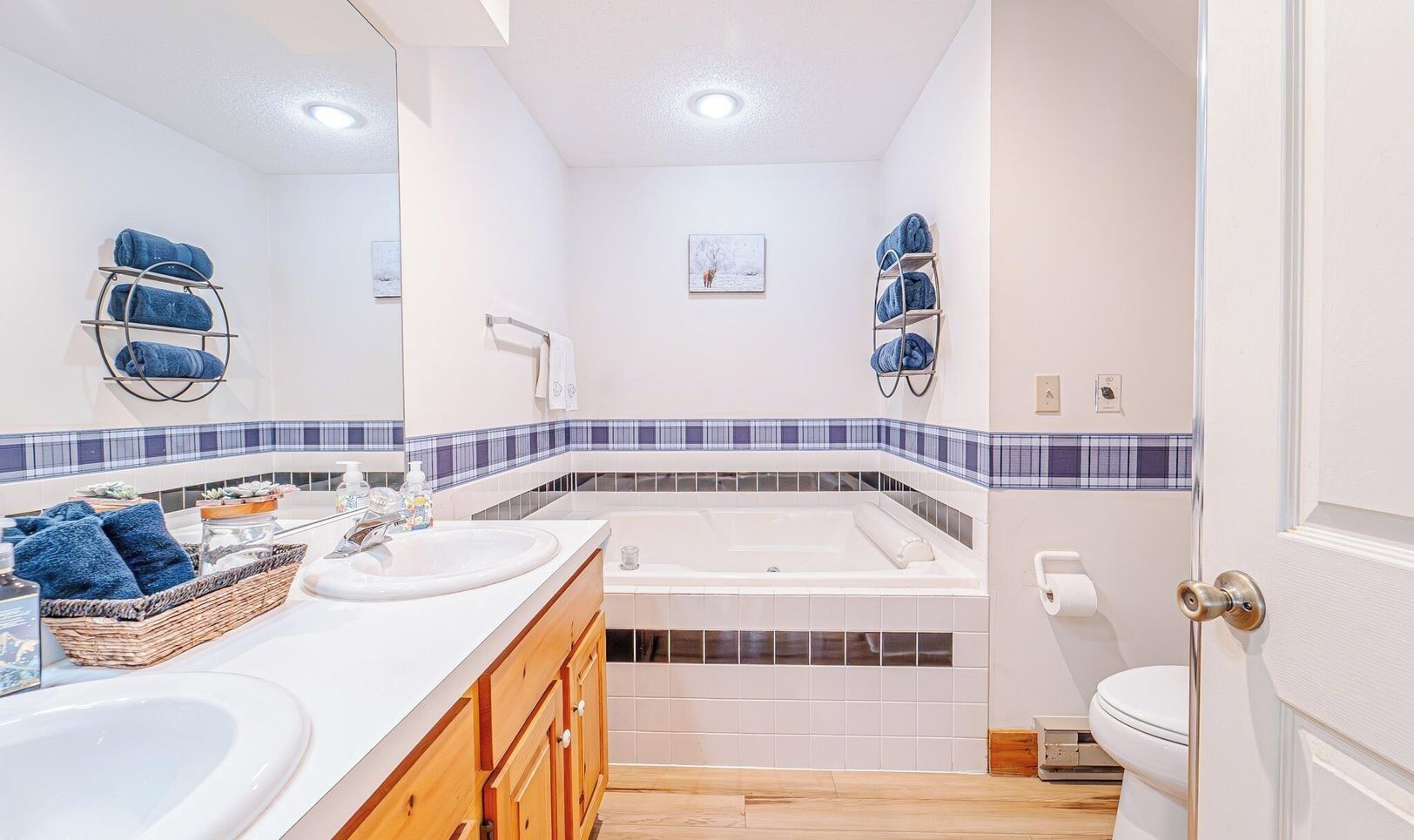 Et moderne badeværelse med to vaske, et badekar og et toilet. Der er håndklæder og toiletartikler på bordet.