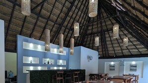 A spacious indoor area with high ceilings, wooden tables and chairs, and hanging light fixtures. - Magic Xcacel Tulum (Tulum)