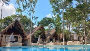 A pool area with thatched-roof huts and lounge chairs. - Magic Xcacel Tulum (Tulum)