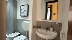 A modern bathroom with a toilet, bidet, and sink. - Station Apartment West (La Spezia)