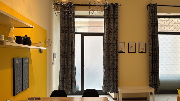 A modern dining area with a wooden table, black chairs, and geometric pendant lights. - Station Apartment West (La Spezia)