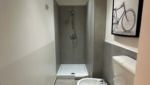 A narrow bathroom with a shower, toilet, and sink. - Station Apartment West (La Spezia)