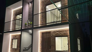 A modern building with a brick facade, multiple balconies, and a staircase leading to an upper level. - Apartamentos Bora Bora Hospedagens (Joinville)