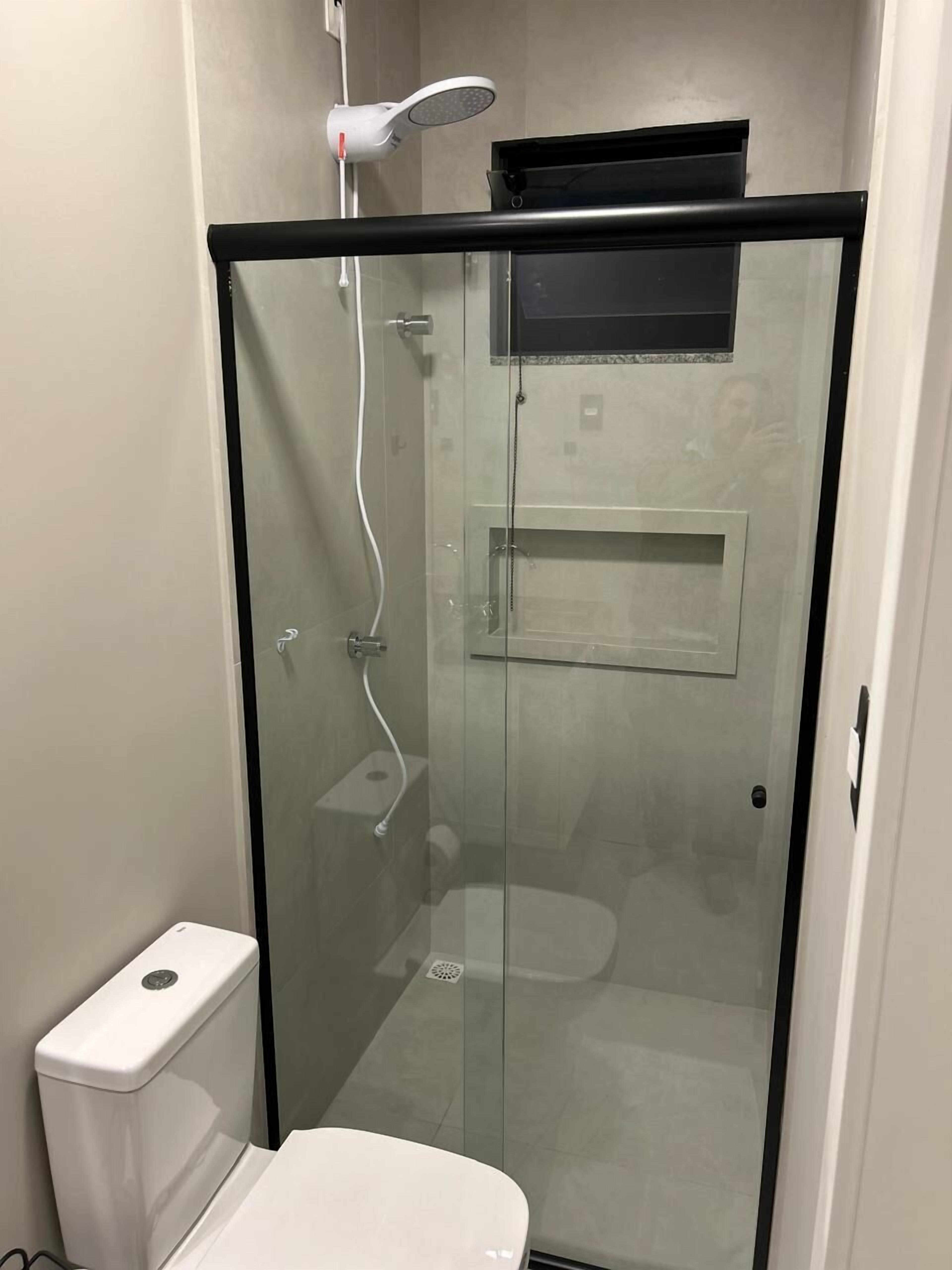 Cabina doccia con pareti in vetro e un water bianco a sinistra.