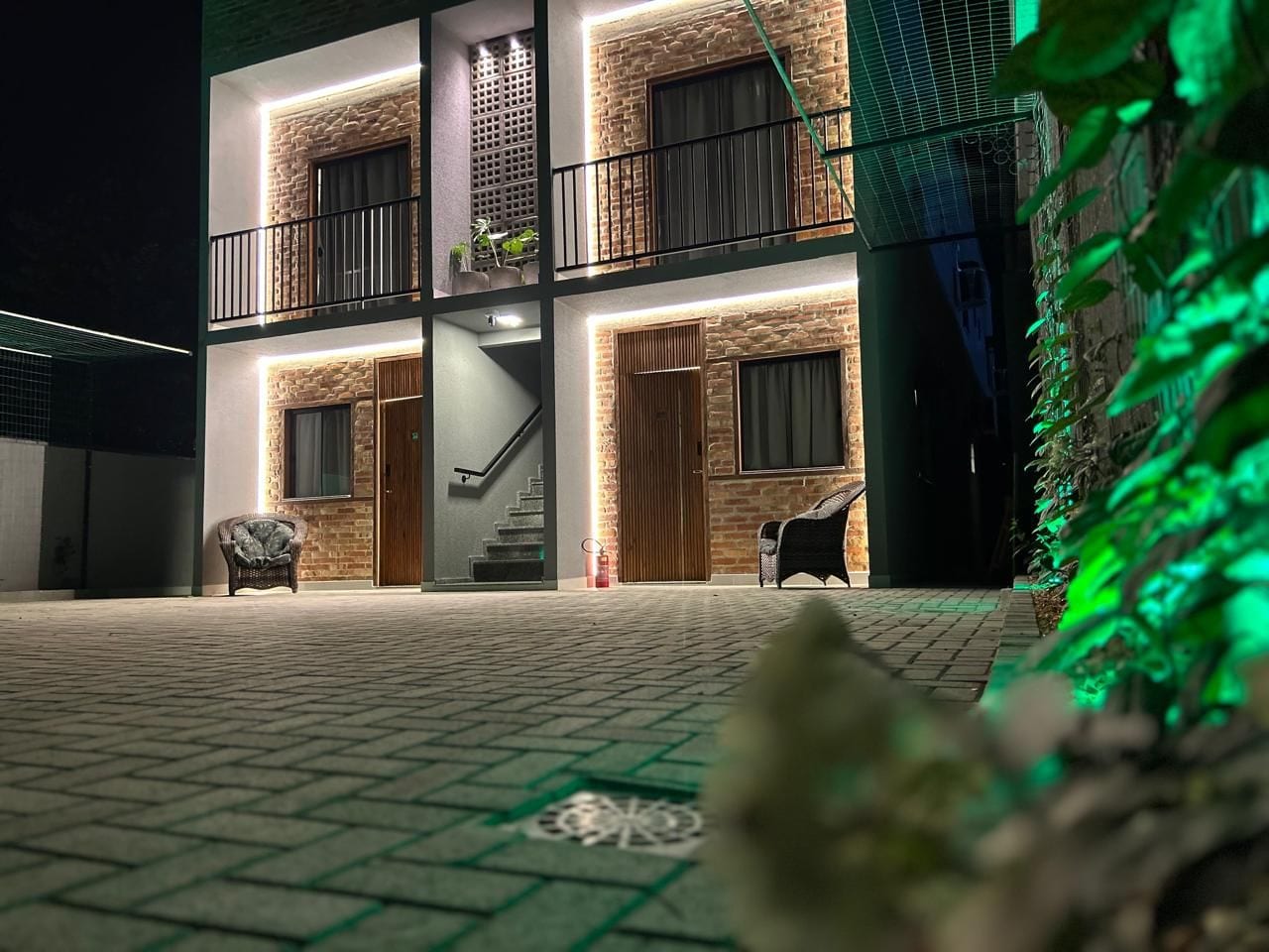 Ein zweistöckiges Gebäude mit einer Stein-Fassade, einem Balkon und einer Treppe, die zum oberen Stock führt.