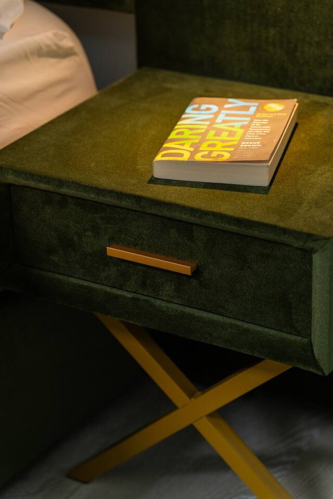 Una mesita de noche tapizada en verde con un libro titulado 'Daringly Green' encima.