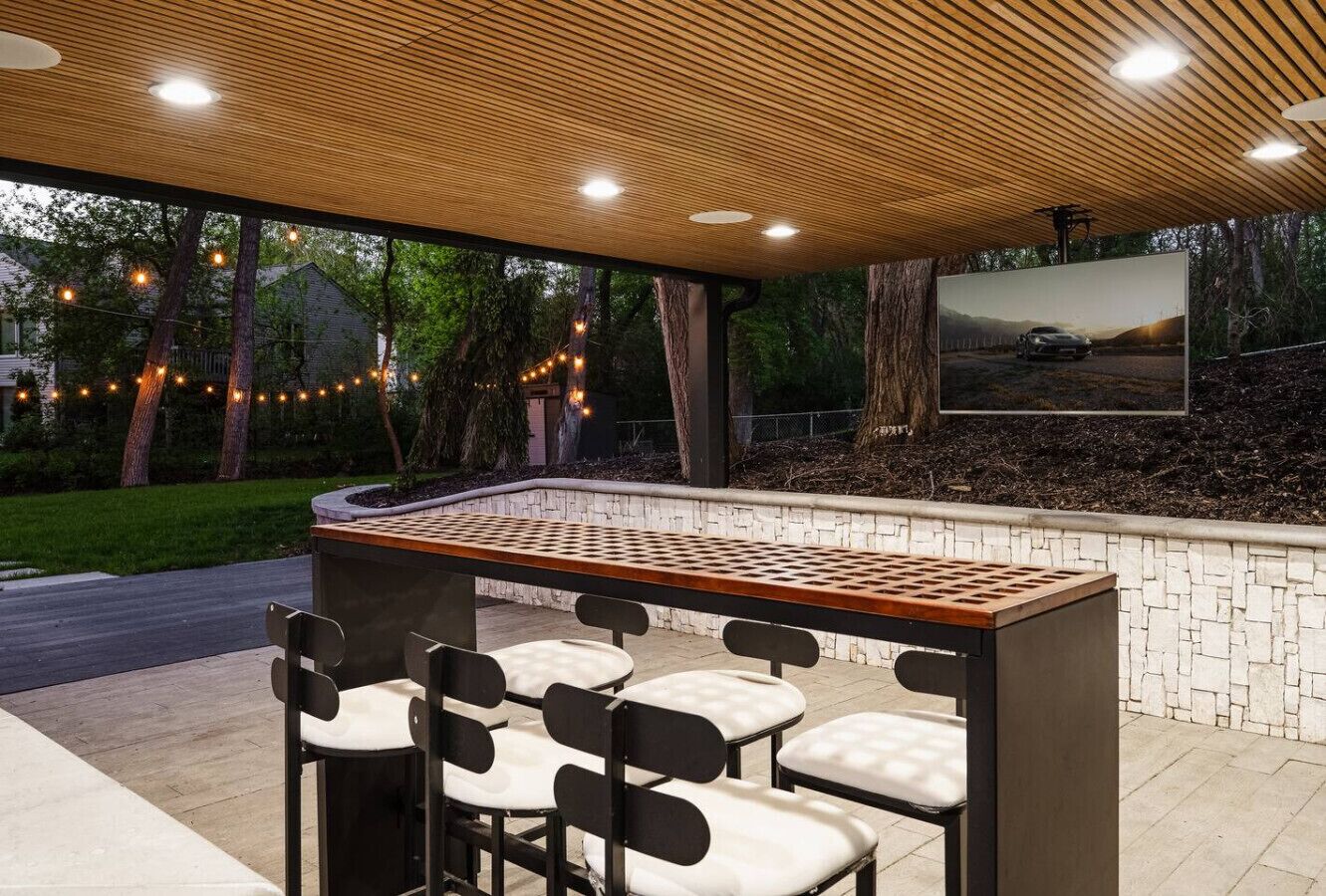 Un espace bar extérieur doté d’un comptoir en bois et de quatre chaises.