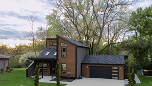Ein modernes, zweistöckiges Haus mit Garage, überdachter Veranda und gepflegtem Rasen.