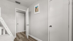 Ein Flur mit weißen Wänden, Holzboden und einer Treppe, die in ein weiteres Zimmer führt.