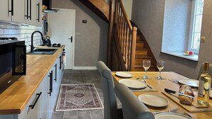 A modern kitchen with wooden countertops, a built-in stove, and a dining area with a table set for two.