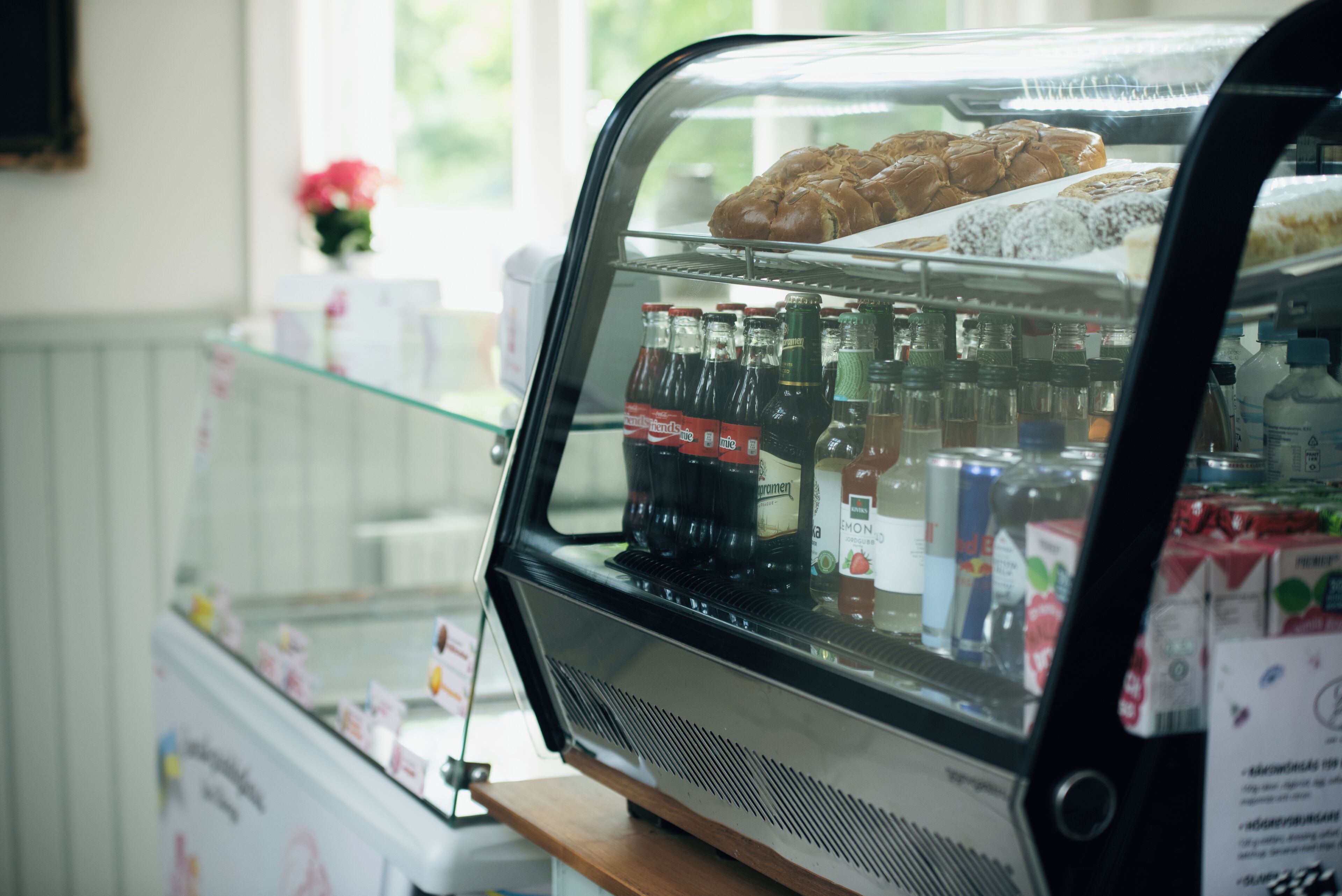 Une vitrine de boulangerie où sont exposées des pâtisseries et des bouteilles de soda.