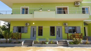 A two-story building with a green facade, multiple windows with shutters, and outdoor seating. - Vila 42 (Vlore)