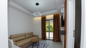 A modern living room with a beige sofa, a small round table, and a patterned rug. - Vila 42 (Vlore)