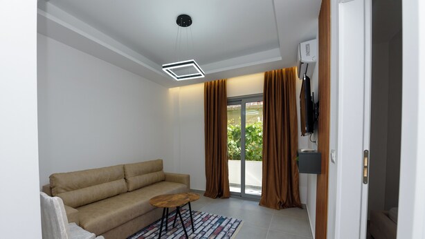 A modern living room with a beige sofa, a small round table, and a patterned rug. - Vila 42 (Vlore)