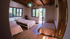 A bedroom with two beds, wooden flooring, a ceiling fan, and large windows. - Casa Grande Lomas de Cocoyoc (Fraccionamiento Lomas de Cocoyoc)