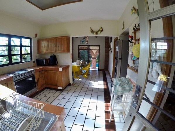 A kitchen with wooden cabinets, a stove, and a dining area with yellow chairs.
