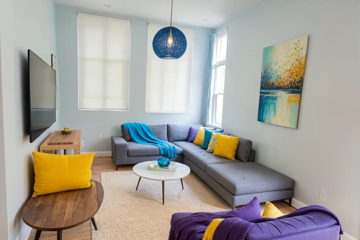 A modern living room with a grey sectional sofa, a round coffee table, and a purple armchair.