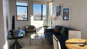 Un salon moderne avec un canapé, un fauteuil, une table basse et un téléviseur posé sur un meuble.