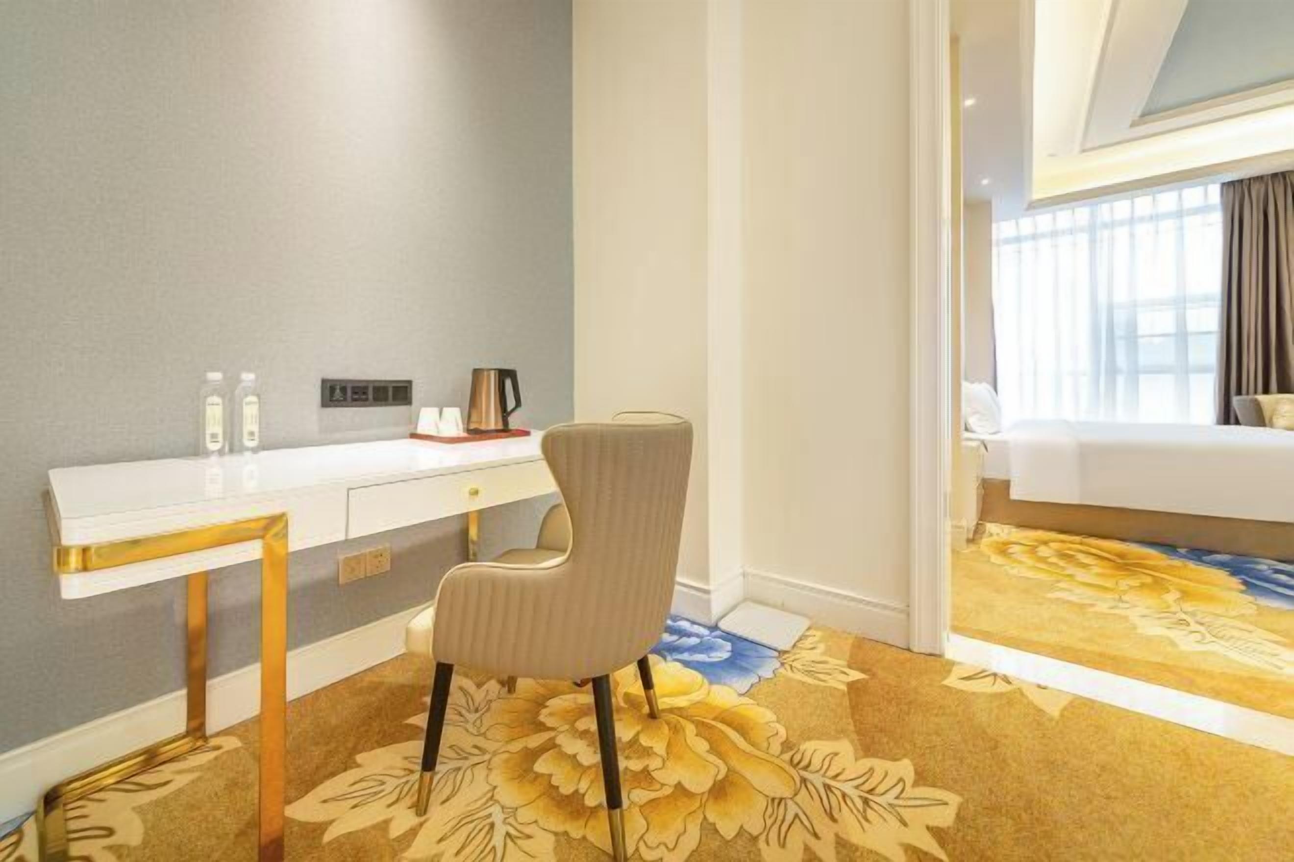 Una habitación de hotel con escritorio, silla, cama y alfombra estampada.
