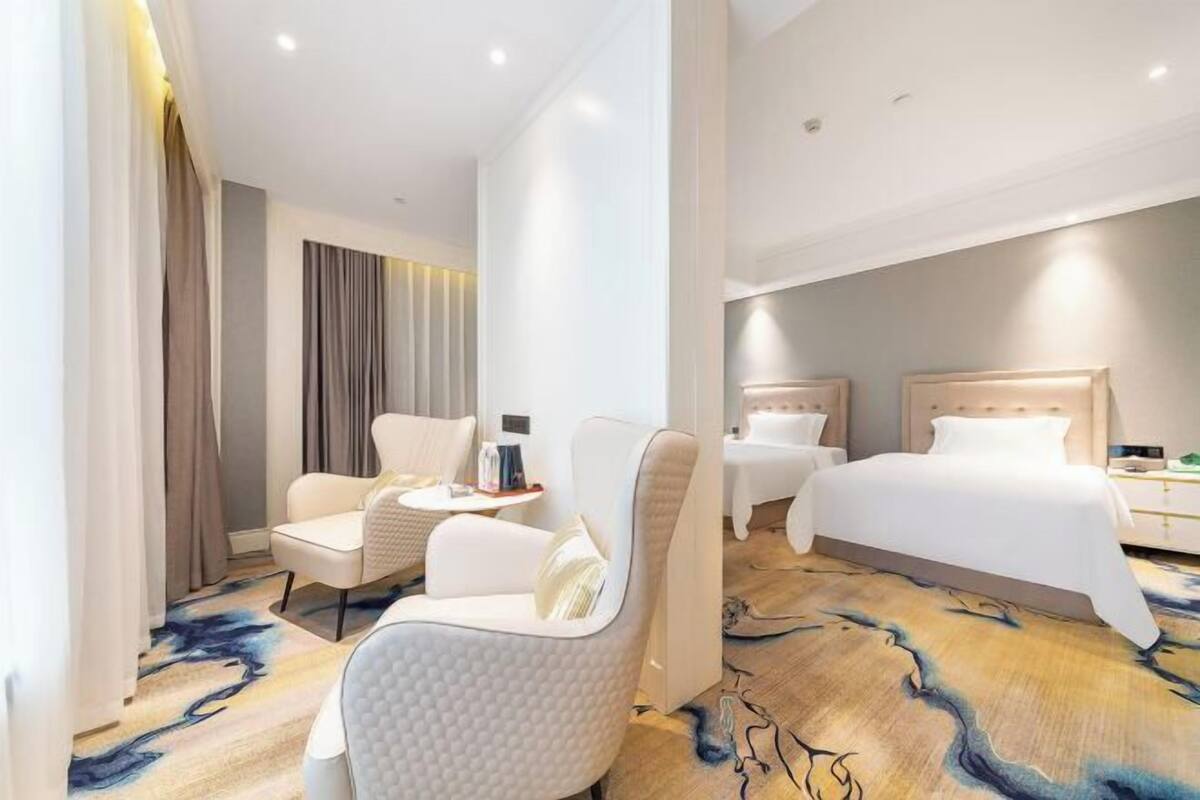 A hotel room with a bed, two chairs, a small table, and a carpet with a river-like design.
