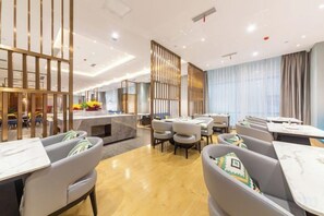 Un hall d’hôtel moderne comprenant un comptoir d’accueil, un espace salon et une vue sur la salle à manger.
