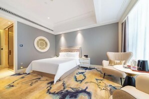 Une chambre d’hôtel moderne avec un grand lit, un élément décoratif rond fixé au mur, une table d’appoint et un canapé.