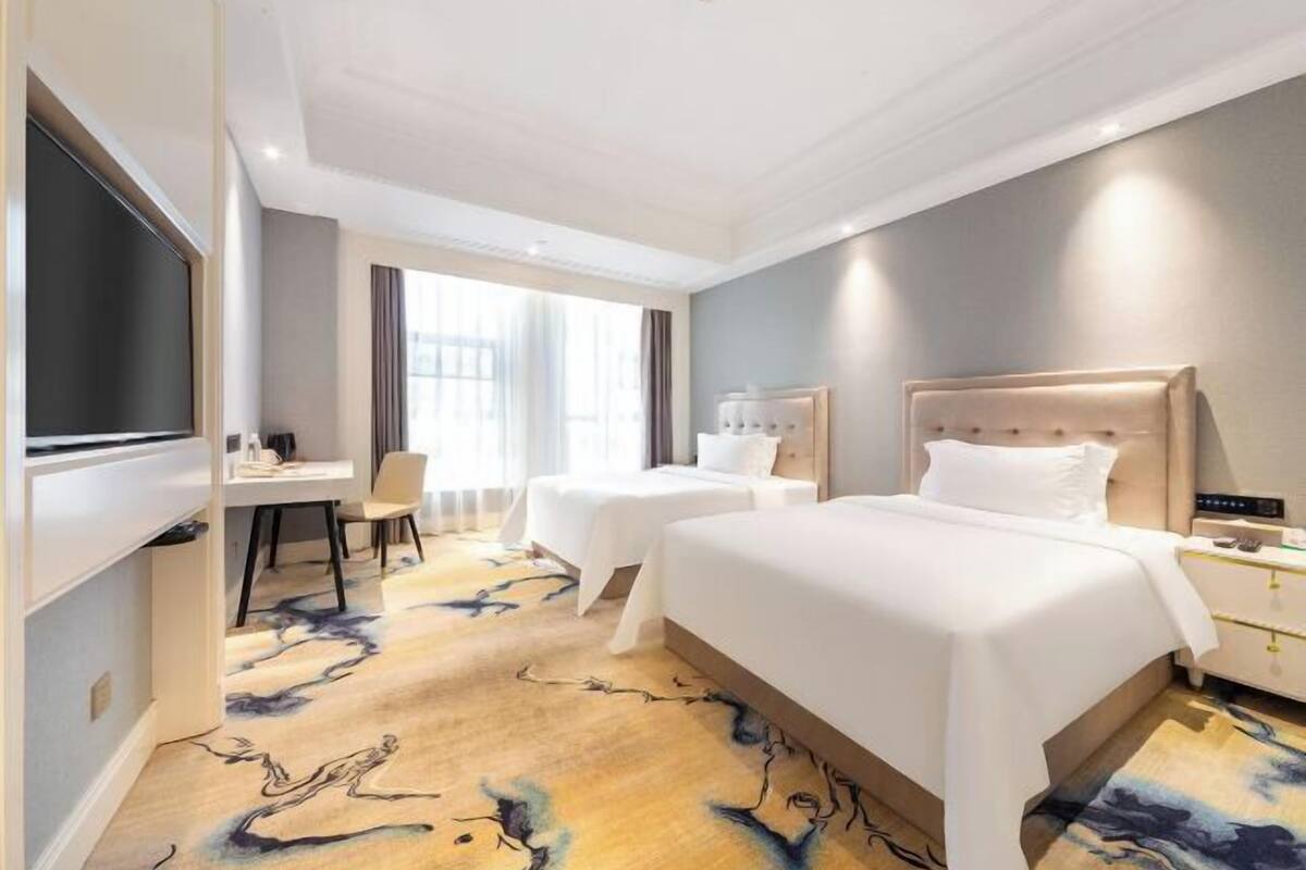 A hotel room with a large bed, two bedside tables, a desk, and a TV.