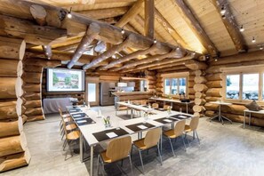 A log cabin-style room with a long table and chairs, a kitchen area, and a large window. - Hotel Kemmeriboden-Bad AG (Schangnau)