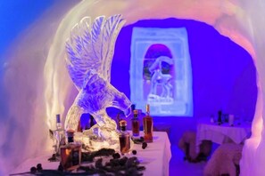 Escultura de hielo de un águila con botellas y una proyección al fondo.