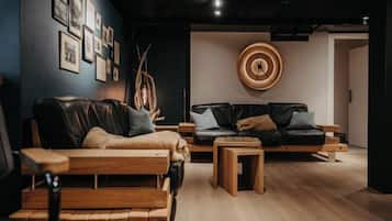 Een moderne woonkamer met een houten bank, een leren bank in zwart en een salontafel.