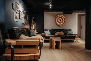 Una sala moderna con un sofá de madera, un sofá de cuero negro y una mesa de centro.