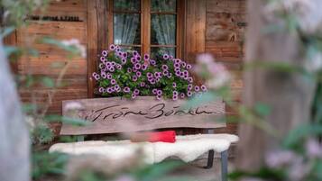 A wooden bench with a floral arrangement in front of a rustic cabin.
