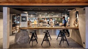 Zona de bar con taburetes, techo de madera y barra con vasos.