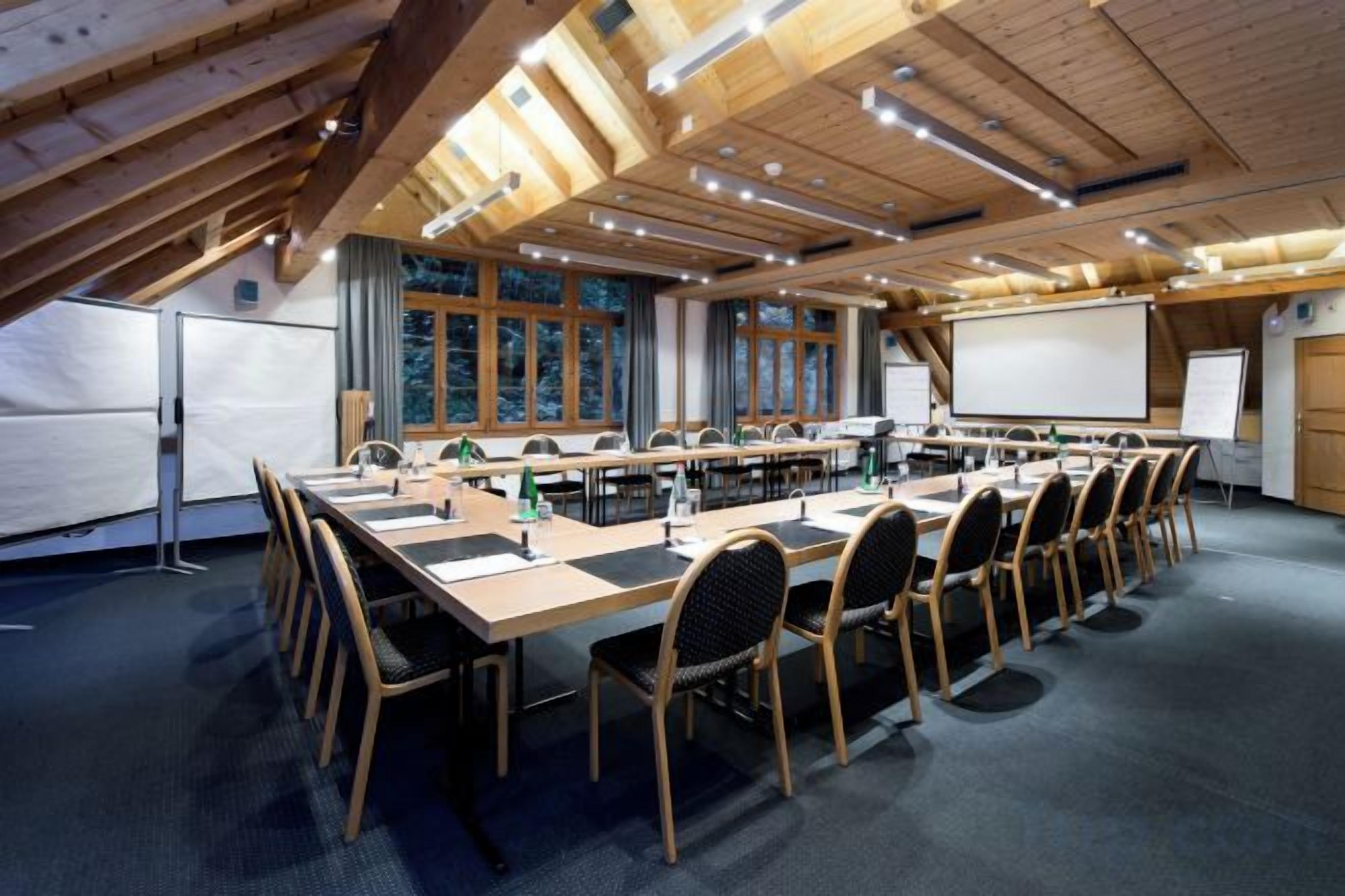 A conference room with a long table, chairs, a projector screen, and a whiteboard.