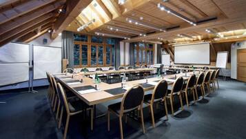 A conference room with a long table, chairs, a projector screen, and a whiteboard.